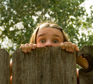 Child peeking over fence
